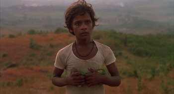 Movie still from “Salaam Bombay!” (1988), directed by Mira Nair – A young boy holding a pair of scissors in his hands; Close Up shot, Low angle