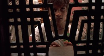 Movie still from “Salaam Bombay!” (1988), directed by Mira Nair – A young man is looking through a grill; Close Up shot, High angle