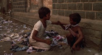 Movie still from “Salaam Bombay!” (1988), directed by Mira Nair – Two young boys are playing with paper on the ground; Medium shot, High angle