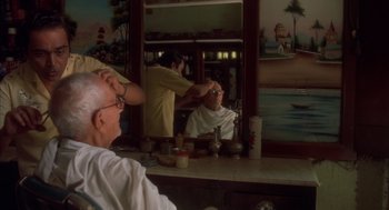 Movie still from “Salaam Bombay!” (1988), directed by Mira Nair – An older man getting his hair cut in a barber shop; Medium shot, Over the shoulder angle