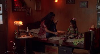 Movie still from “Salaam Bombay!” (1988), directed by Mira Nair – A woman and a child sitting on a bed; Wide shot, High angle