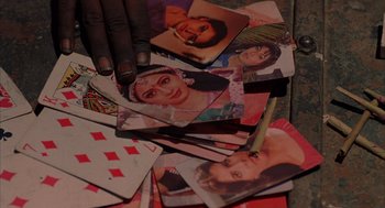 Movie still from “Salaam Bombay!” (1988), directed by Mira Nair – A hand is holding onto a pile of pictures; Extreme Close Up shot, Overhead angle