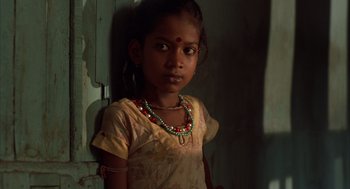 Movie still from “Salaam Bombay!” (1988), directed by Mira Nair – A young girl wearing a yellow shirt and a red necklace; Close Up shot, High angle
