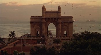 Movie still from “Salaam Bombay!” (1988), directed by Mira Nair – People are gathered in front of a large stone arch; Extreme Wide shot, High angle