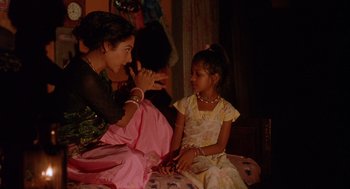 Movie still from “Salaam Bombay!” (1988), directed by Mira Nair – A woman sitting next to a girl on a bed; Medium shot, Over the shoulder angle