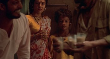 Movie still from “Salaam Bombay!” (1988), directed by Mira Nair – A woman standing next to a boy holding a glass; Close Up shot, High angle
