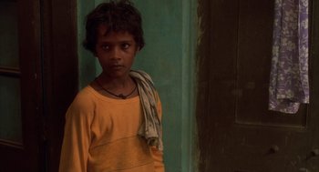 Movie still from “Salaam Bombay!” (1988), directed by Mira Nair – A young boy in a yellow shirt and a scarf around his neck; Close Up shot, High angle