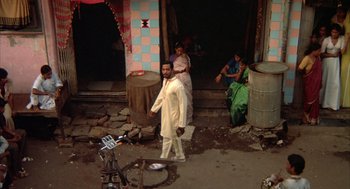 Movie still from “Salaam Bombay!” (1988), directed by Mira Nair – A man and woman standing in front of a building; Wide shot, High angle