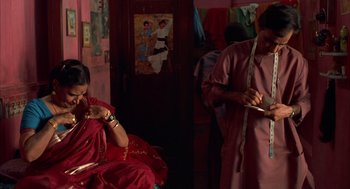 Movie still from “Salaam Bombay!” (1988), directed by Mira Nair – A woman sitting in a chair next to a man; Medium shot, Low angle