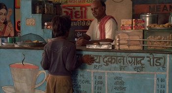 Movie still from “Salaam Bombay!” (1988), directed by Mira Nair – A man standing at a counter with a woman at the counter; Medium shot, High angle