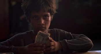 Movie still from “Salaam Bombay!” (1988), directed by Mira Nair – A young boy is holding money in his hands; Close Up shot, Over the shoulder angle