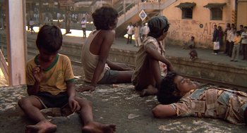 Movie still from “Salaam Bombay!” (1988), directed by Mira Nair – A group of children sitting on the ground near a building; Wide shot, High angle