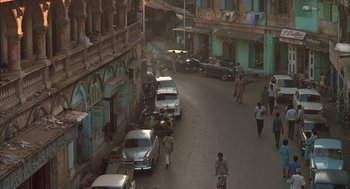 Movie still from “Salaam Bombay!” (1988), directed by Mira Nair – A street scene with cars parked on both sides of the street; Extreme Wide shot, High angle