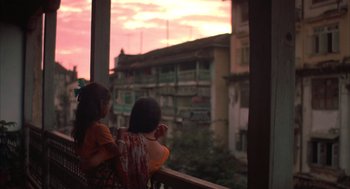 Movie still from “Salaam Bombay!” (1988), directed by Mira Nair – Two young girls are looking out of a window at the sunset; Wide shot, Low angle