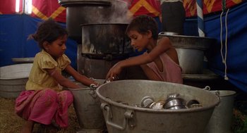Movie still from “Salaam Bombay!” (1988), directed by Mira Nair – Two young children are washing dishes in large pots; Medium shot, High angle