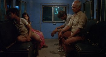 Movie still from “Salaam Bombay!” (1988), directed by Mira Nair – A group of people sitting on a train; Wide shot, High angle