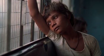 Movie still from “Salaam Bombay!” (1988), directed by Mira Nair – A young boy leaning up against a metal fence; Close Up shot, High angle