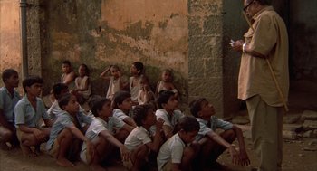 Movie still from “Salaam Bombay!” (1988), directed by Mira Nair – A group of young boys sitting in front of an old building; Wide shot, High angle
