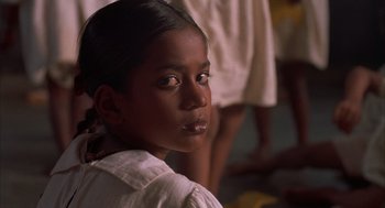 Movie still from “Salaam Bombay!” (1988), directed by Mira Nair – A young girl is sitting in front of a group of people; Close Up shot, High angle