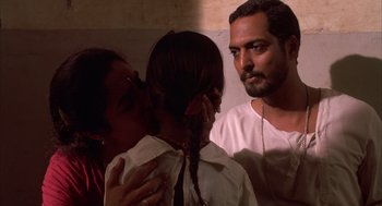 Movie still from “Salaam Bombay!” (1988), directed by Mira Nair – A man and a woman standing next to a girl; Close Up shot, Over the shoulder angle