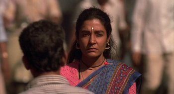 Movie still from “Salaam Bombay!” (1988), directed by Mira Nair – A woman in a pink and blue sari stares at the camera; Close Up shot, Over the shoulder angle