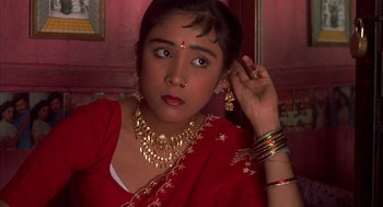 Movie still from “Salaam Bombay!” (1988), directed by Mira Nair – A woman in a red sari wearing gold jewelry; Close Up shot, High angle