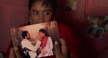 Movie still from “Salaam Bombay!” (1988), directed by Mira Nair – A woman holding up a picture of a man and a woman; Extreme Close Up shot, High angle