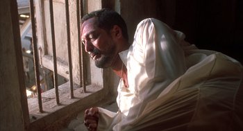 Movie still from “Salaam Bombay!” (1988), directed by Mira Nair – A man sitting in front of a window with his eyes closed; Close Up shot, Low angle