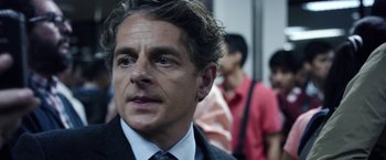 Movie still from “Salt and Fire” (2016), directed by Werner Herzog – A person wearing a suit and tie; Close Up shot, Over the shoulder angle