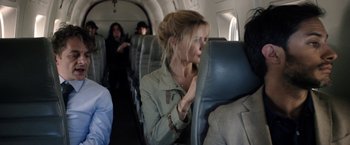 Movie still from “Salt and Fire” (2016), directed by Werner Herzog – A woman sitting on a seat on an airplane; Medium shot, Over the shoulder angle
