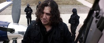 Movie still from “Salt and Fire” (2016), directed by Werner Herzog – A man with long black hair wearing a black jacket; Close Up shot, Over the shoulder angle