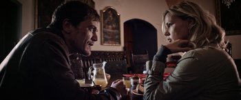 Movie still from “Salt and Fire” (2016), directed by Werner Herzog – A man and a woman sitting at a table with drinks in front of them; Medium shot, Over the shoulder angle