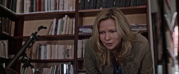 Movie still from “Salt and Fire” (2016), directed by Werner Herzog – A woman leaning on the floor in front of a book shelf; Medium shot, Over the shoulder angle