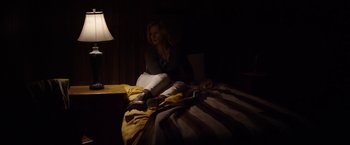Movie still from “Salt and Fire” (2016), directed by Werner Herzog – A woman sitting on a bed in a dark room; Wide shot, Low angle