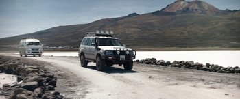 Movie still from “Salt and Fire” (2016), directed by Werner Herzog – A white truck driving down a dirt road; Wide shot, High angle