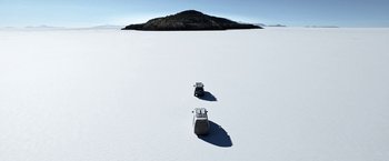 Movie still from “Salt and Fire” (2016), directed by Werner Herzog – Two lawn chairs in the middle of a snow covered field; Extreme Wide shot, High angle