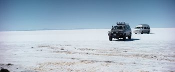 Movie still from “Salt and Fire” (2016), directed by Werner Herzog – A truck is parked on the side of the road in the snow; Extreme Wide shot, Low angle
