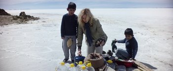 Movie still from “Salt and Fire” (2016), directed by Werner Herzog – A woman and a boy standing in front of a pile of water bottles; Medium shot, High angle