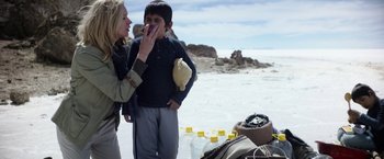 Movie still from “Salt and Fire” (2016), directed by Werner Herzog – A woman and a boy standing on a beach near water bottles; Medium shot, Over the shoulder angle