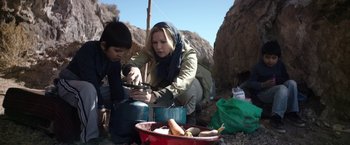 Movie still from “Salt and Fire” (2016), directed by Werner Herzog – A woman and a boy cooking food on a pot; Medium shot, Over the shoulder angle
