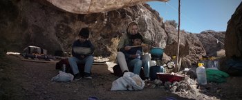 Movie still from “Salt and Fire” (2016), directed by Werner Herzog – A woman and two children sitting on a rock; Medium shot, Low angle
