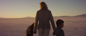 Movie still from “Salt and Fire” (2016), directed by Werner Herzog – A woman and two children holding hands on a beach; Medium shot, Low angle