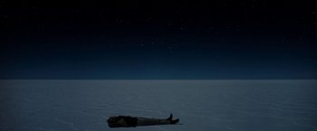 Movie still from “Salt and Fire” (2016), directed by Werner Herzog – A man laying on the ground in the middle of the night; Extreme Wide shot, Overhead angle