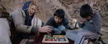 Movie still from “Salt and Fire” (2016), directed by Werner Herzog – A woman and a child playing a board game; Medium shot, Over the shoulder angle