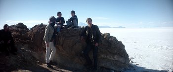 Movie still from “Salt and Fire” (2016), directed by Werner Herzog – A group of people sitting on top of a rock; Wide shot, Low angle