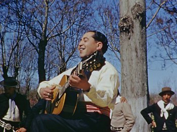 Movie still from “Saludos Amigos” (1942), directed by Jack Kinney – A man sitting in front of a tree holding a guitar; Medium shot, Low angle