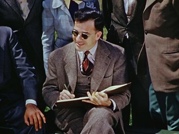 Movie still from “Saludos Amigos” (1942), directed by Jack Kinney – A man in a suit and tie writing in a notebook; Medium shot, High angle