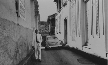Movie still from “Salut les Cubains” (1963), directed by Agnès Varda – A man standing in the middle of an alley; Wide shot, Low angle