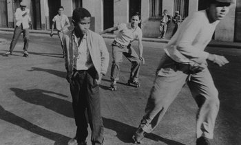 Movie still from “Salut les Cubains” (1963), directed by Agnès Varda – A black and white photo of a group of skateboarders; Wide shot, Low angle