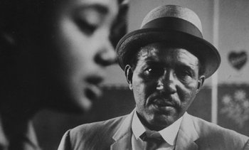 Movie still from “Salut les Cubains” (1963), directed by Agnès Varda – A man wearing a suit and a hat; Close Up shot, Low angle
